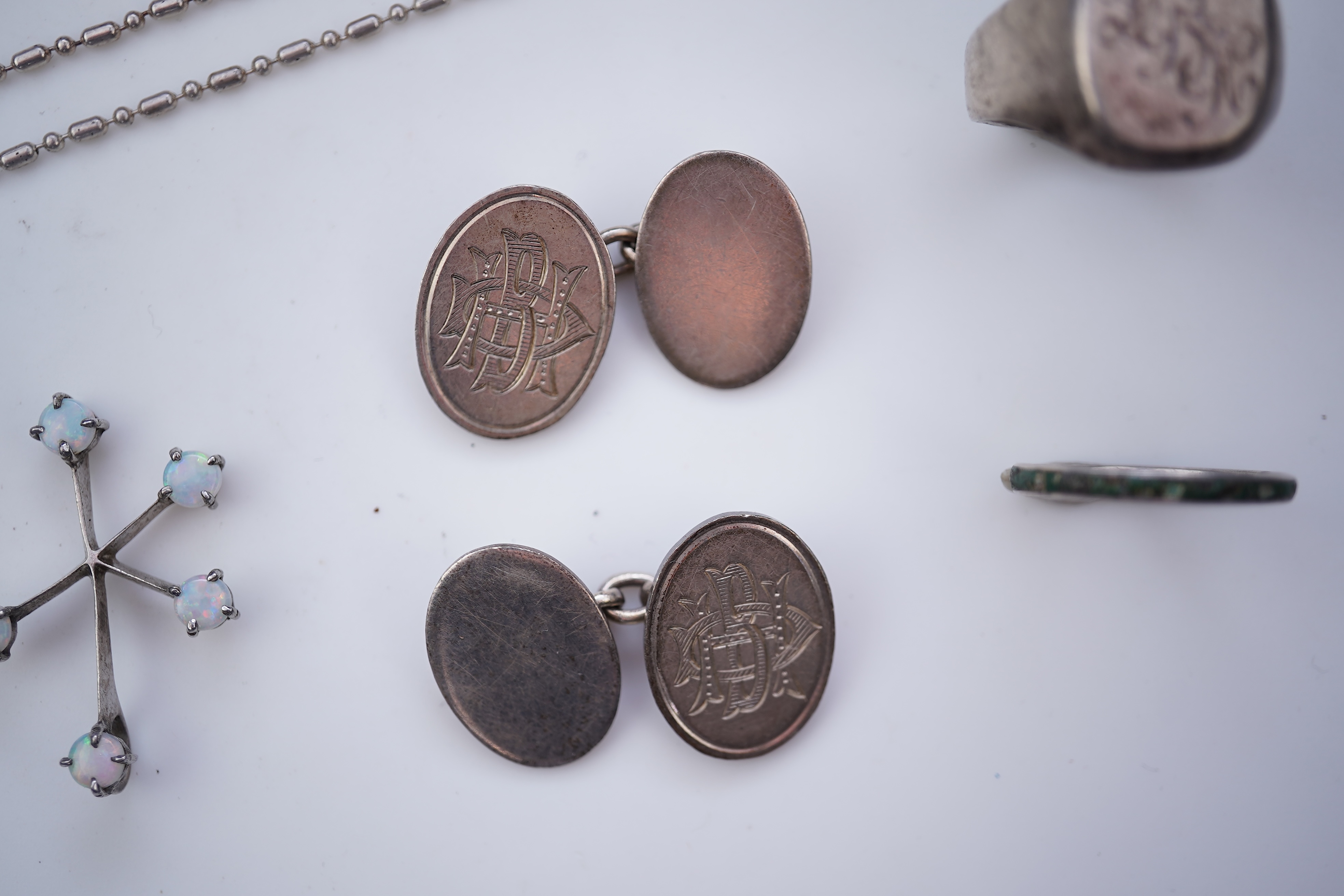 A collection of silver jewels, comprising: a bangle; a chain necklace suspending two winding toothpicks, one with toothpick deficient; a rope twist chain; a pair of cufflinks with the initials DBH; a pendant of abstract